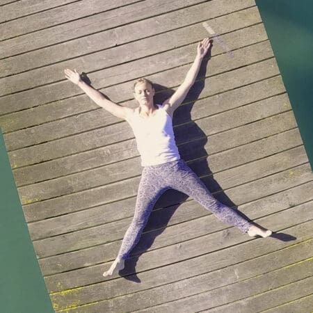 Winnie, founder, resting in Savasana on a pier, embracing inner peace and stillness.