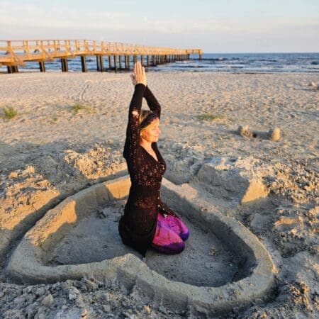 Winnie, founder, in meditation pose inside heart on the beach on yoga retreat in Sweden.